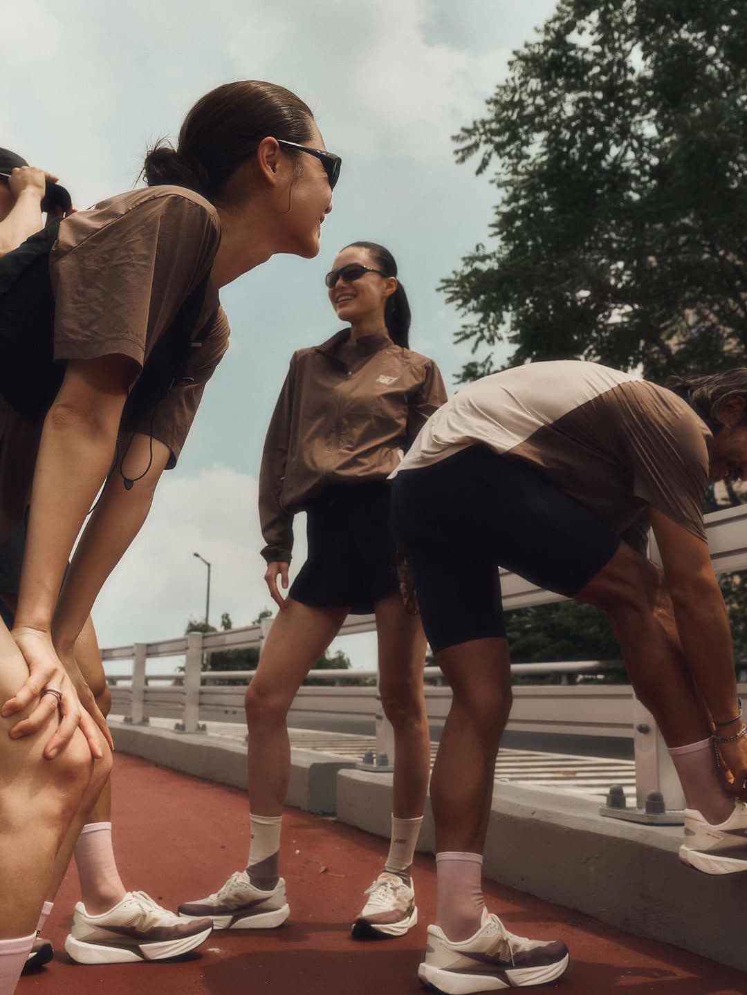 Trois personnes en tenue de running échangent un regard complice après la séance, sur une passerelle urbaine