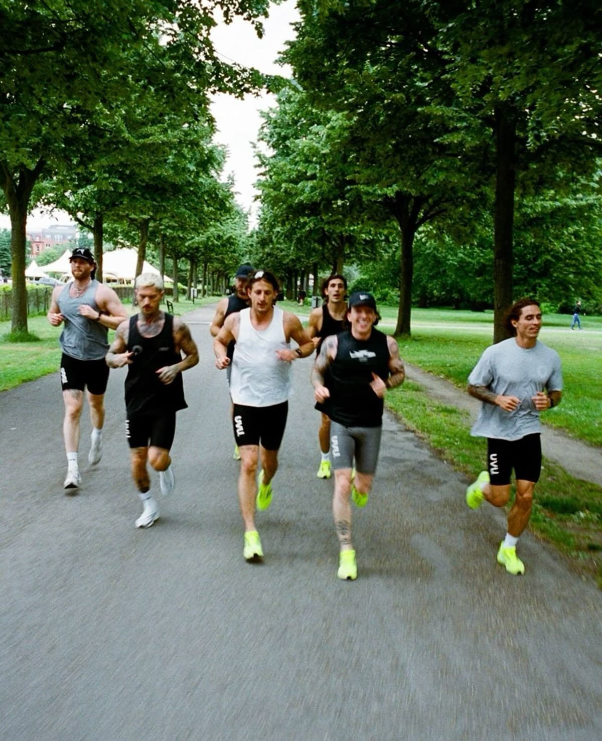 Groupe de coureurs sur un chemin arboré d'un parc en matinée, allure décontractée de club de quartier